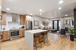 Una cocina moderna con armarios de madera, un refrigerador de acero inoxidable y una isla de mármol.