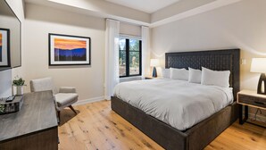Quarto moderno com uma cama grande, uma escrivaninha e uma cadeira.