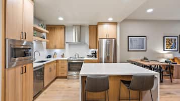 Een moderne keuken met houten kastjes, roestvrijstalen apparatuur en een marmeren aanrecht.