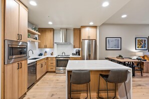 A modern kitchen with wooden cabinets, stainless steel appliances, and a marble countertop. - Impeccable Condo|Close to Dining Options (Tamarack)