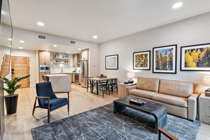 A modern living room with a sofa, a coffee table, and a dining area with chairs.