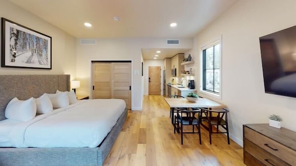 Une chambre d’hôtel avec un grand lit, un bureau et une kitchenette.