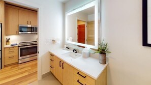 Une cuisine moderne avec des meubles en bois, des appareils en acier inoxydable et un plan de travail blanc.