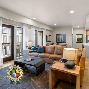 A modern living room with a sofa, coffee table, and a dining area with a table and chairs.