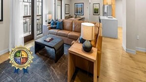Un salon spacieux comprenant un canapé, une table basse et une lampe. Il y a également un coin cuisine avec un réfrigérateur et une table à manger.