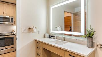 A modern bathroom with a large mirror, a sink, and a built-in oven.