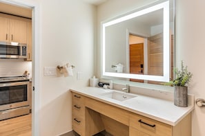 A modern bathroom with a large mirror, a sink, and a built-in oven. - Impeccable Condo|Pet Friendly|Juliette Balcony (Tamarack)