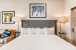 A hotel room with a large bed, two side tables with lamps, a sofa with cushions, and two framed artworks on the wall. - Impeccable Condo|Pet Friendly|Juliette Balcony (Tamarack)