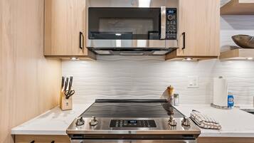 Una cocina con microondas de acero inoxidable, estufa a gas y horno empotrado.