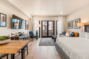 A modern hotel room with a bed, a desk, a chair, a sofa, and a dining table. - Impeccable Condo|Pet Friendly|Juliette Balcony (Tamarack)