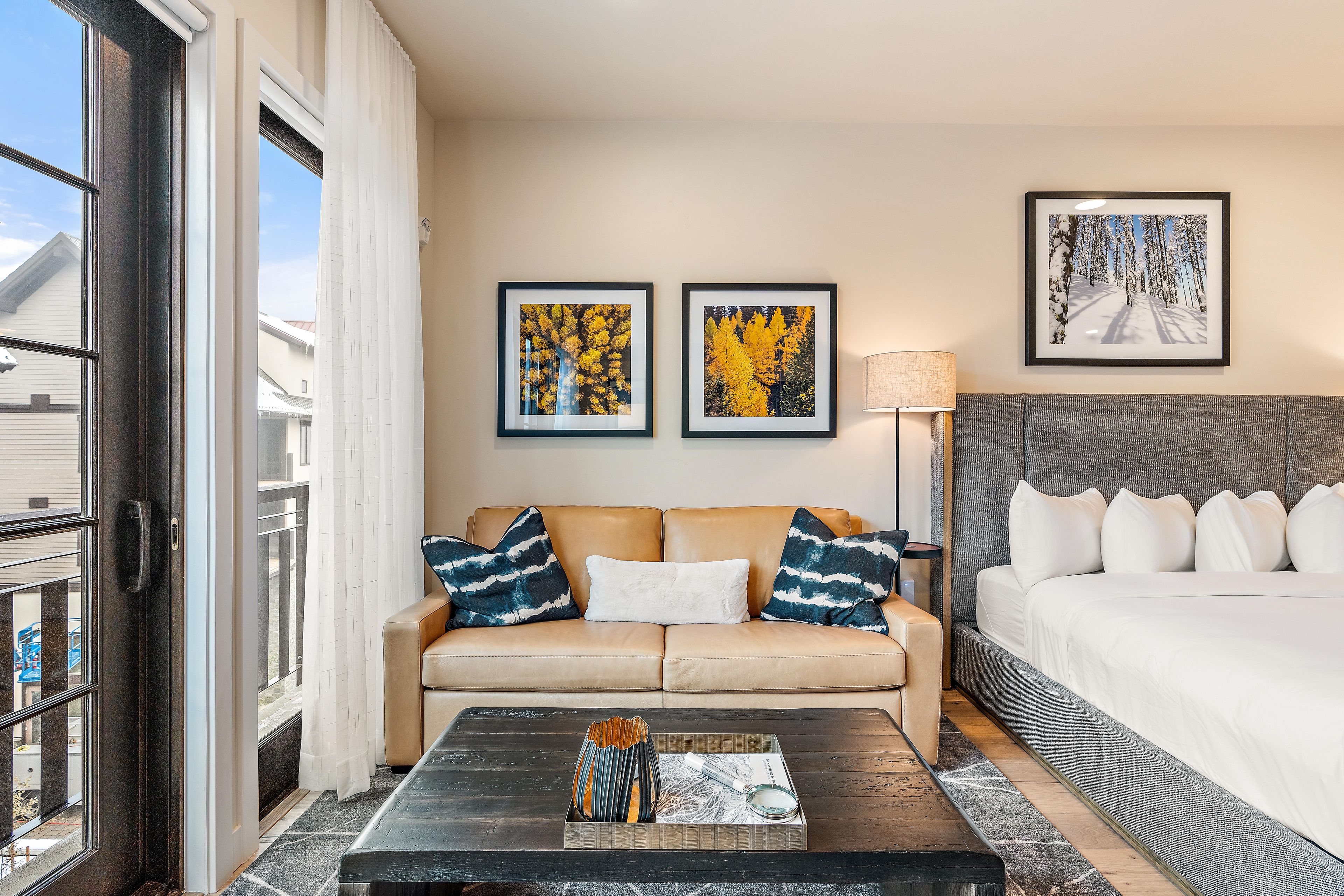 Ein Hotelzimmer mit einer Couch, einem Bett, einem Couchtisch und zwei gerahmten Bildern an der Wand.