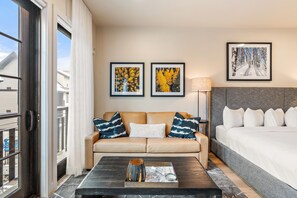 A hotel room with a sofa, a bed, a coffee table, and two framed pictures on the wall.