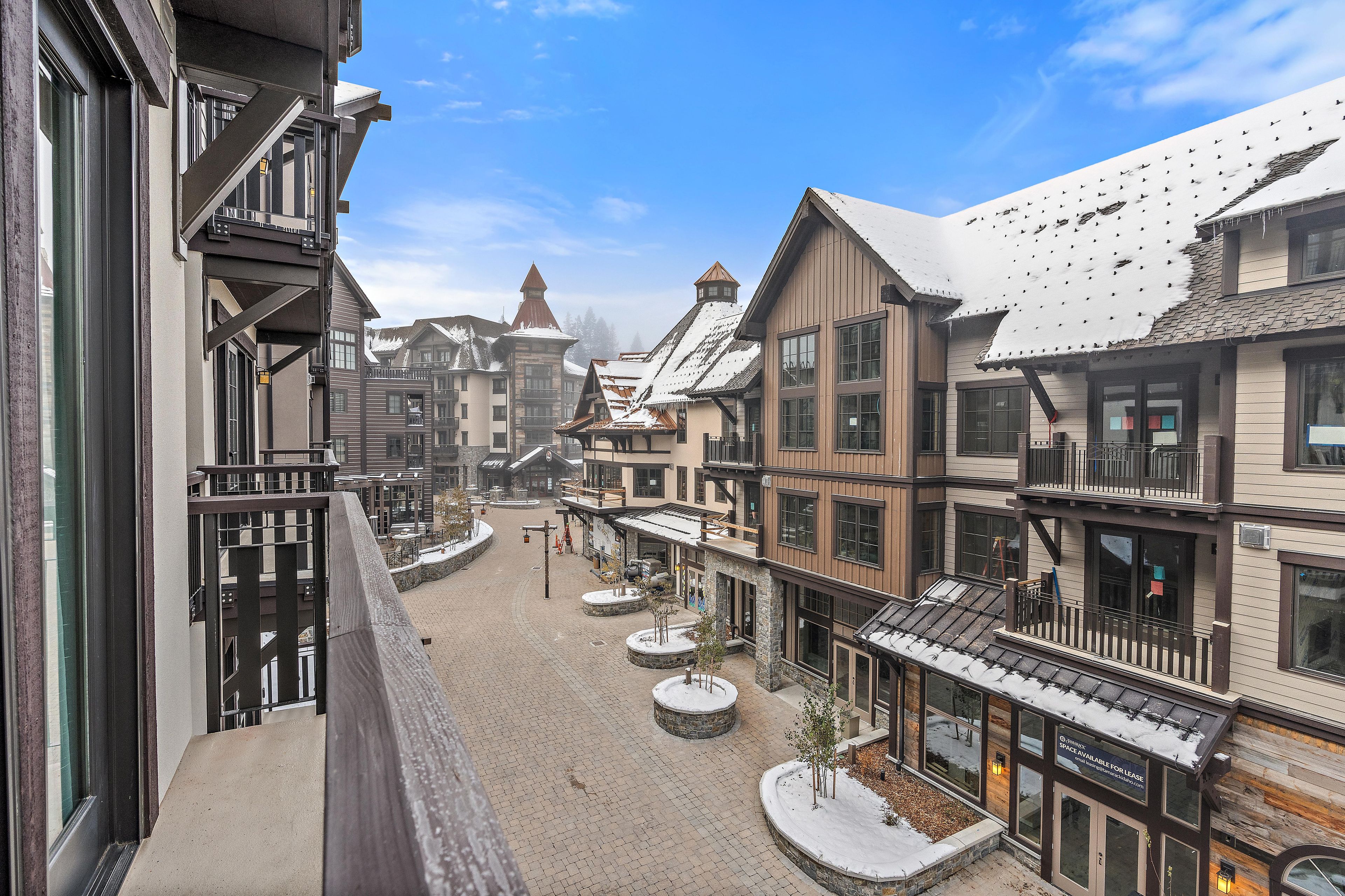A snow-covered town square with buildings featuring balconies and large windows.