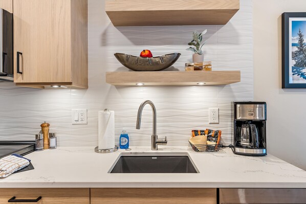 A modern kitchen with a built-in sink, stainless steel faucet, and a coffee maker. - Impeccable Condo|Pet Friendly|Juliette Balcony (Tamarack)