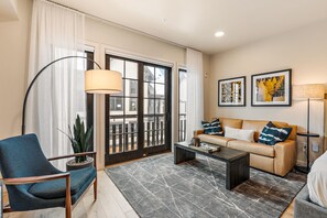 A modern living room with a sofa, armchair, coffee table, and a potted plant. - Impeccable Condo|Pet Friendly|Juliette Balcony (Tamarack)