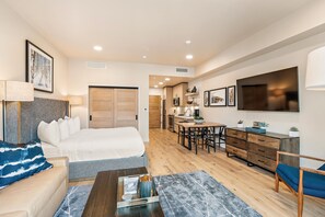 A modern hotel room with a bed, seating area, kitchenette, and a TV. - Impeccable Condo|Pet Friendly|Juliette Balcony (Tamarack)