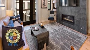 A modern living room with a fireplace, a sofa with cushions, a coffee table, and a TV mounted on the wall.