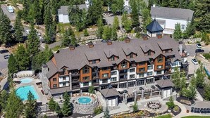 A multi-story lodge with a pool, outdoor seating, and a landscaped garden.