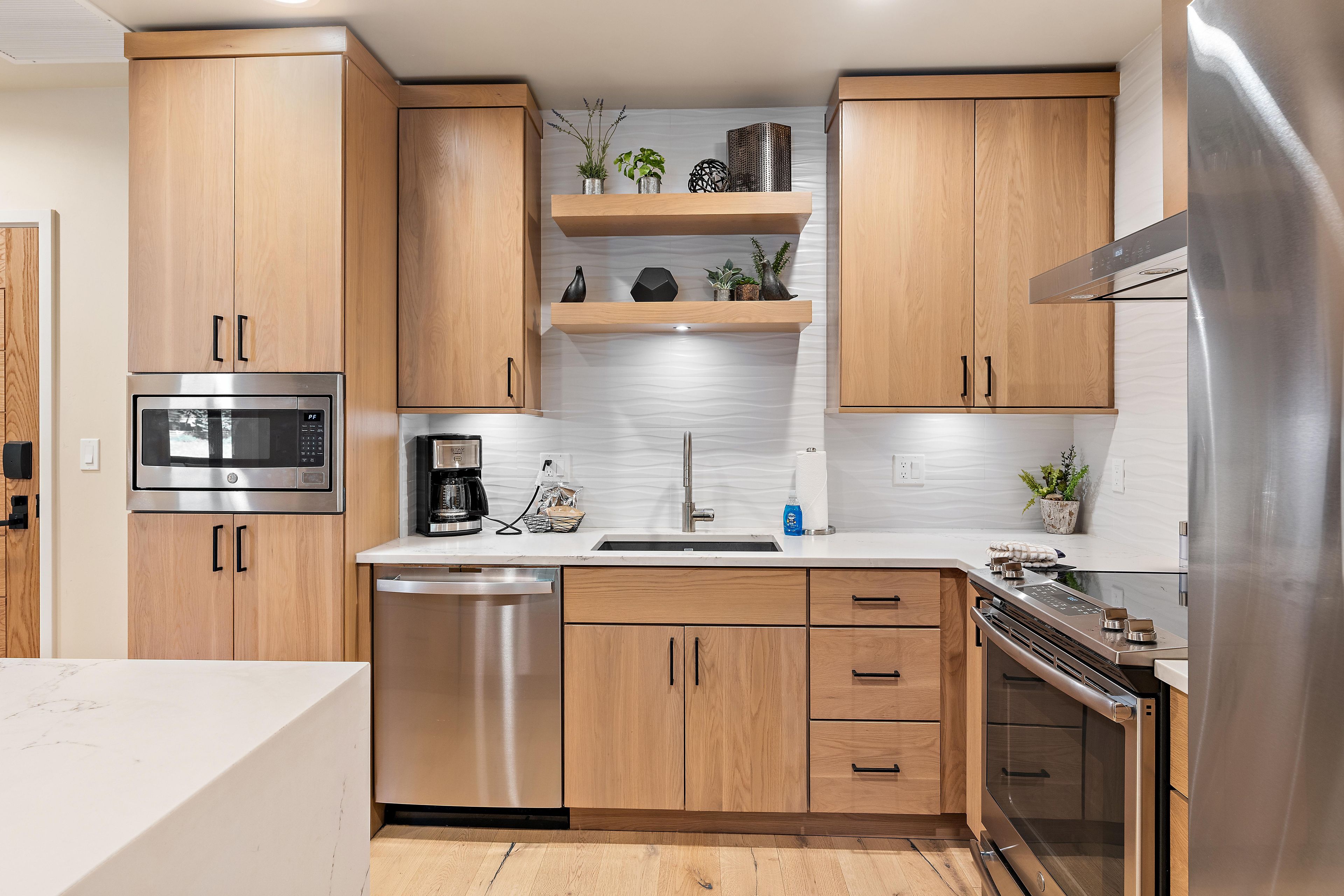 Eine moderne Küche mit Holzausstattung, Edelstahlgeräten und einem eingebauten Backofen.