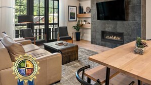A modern living room with a fireplace, a flat-screen TV, and comfortable seating.