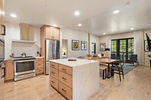 A modern kitchen with wooden cabinets, stainless steel appliances, and a marble island.