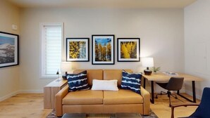 A living room with a beige sofa, two side tables, a wooden coffee table, and three framed pictures on the wall. - Forest Haven | Includes Two 1-Day Lift Tickets (Tamarack)