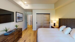 A hotel room with a bed, a TV, a dresser, and a door leading to a closet.