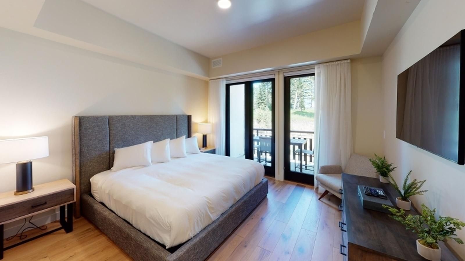Una habitación de hotel moderna con una cama grande, un escritorio, una silla y un televisor.