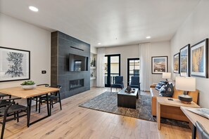 A modern living room with a fireplace, a dining area, and a seating area with a sofa and armchairs.