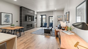 Een moderne woonkamer met een open haard, een eethoek en zitplaatsen met uitzicht op de omgeving.