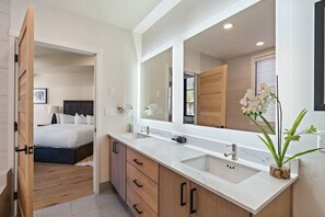 Een moderne badkamer met een grote spiegel, twee wastafels en een houten wastafelmeubel.