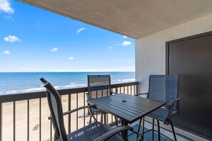 Ein Balkon mit Blick auf den Ozean, ausgestattet mit einem Tisch und zwei Stühlen.