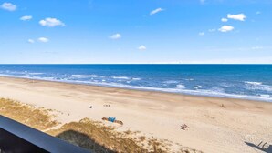Une plage avec un ciel dégagé, une mer calme et quelques personnes.