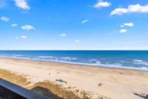 Ein Strand mit blauem Himmel, ruhiger See und wenigen Personen.