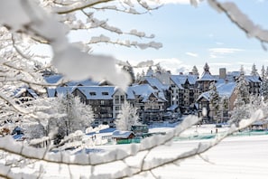 Un complejo de edificios cubierto de nieve, con varias construcciones, incluyendo un hotel grande de varios pisos y un edificio más pequeño con techo verde.