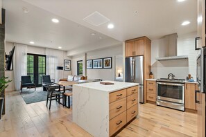 A modern kitchen with a central island, built-in oven, and stainless steel appliances.