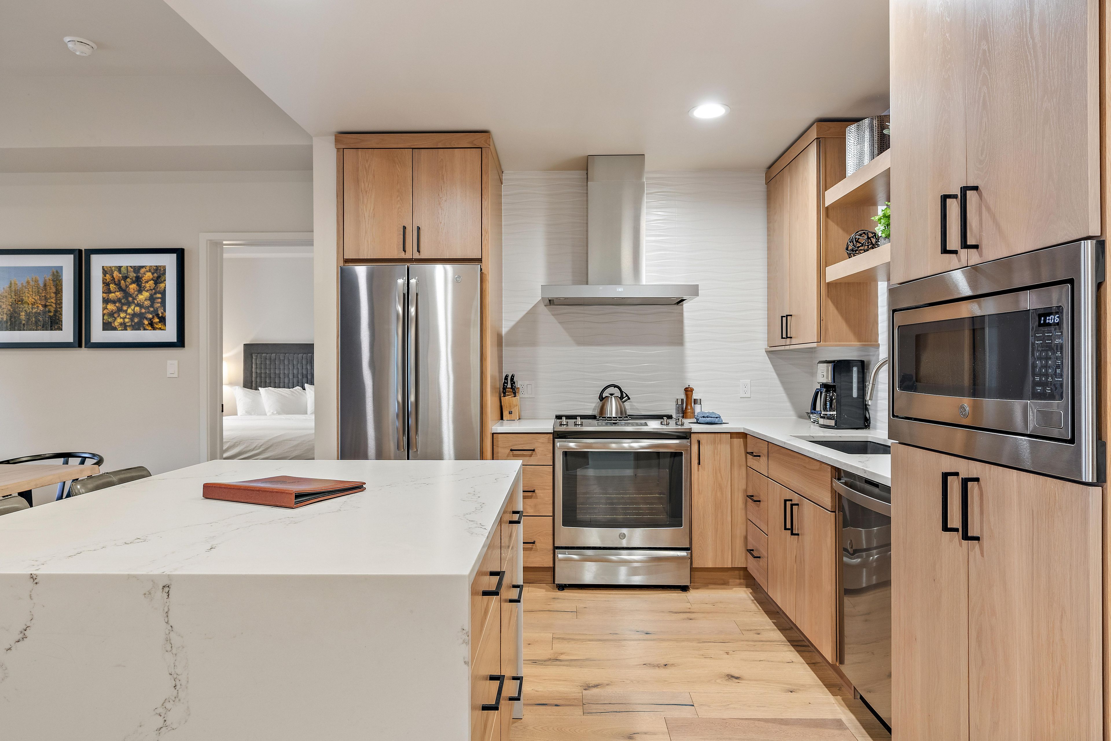 Cocina moderna con electrodomésticos de acero inoxidable, armarios de madera y encimera de mármol.