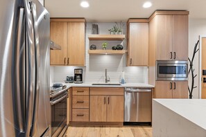 Una cocina moderna con armarios de madera, electrodomésticos de acero inoxidable y encimera blanca.