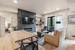 Ein modernes Wohnzimmer mit Kamin, Flachbildfernseher, Sofa und Essbereich.