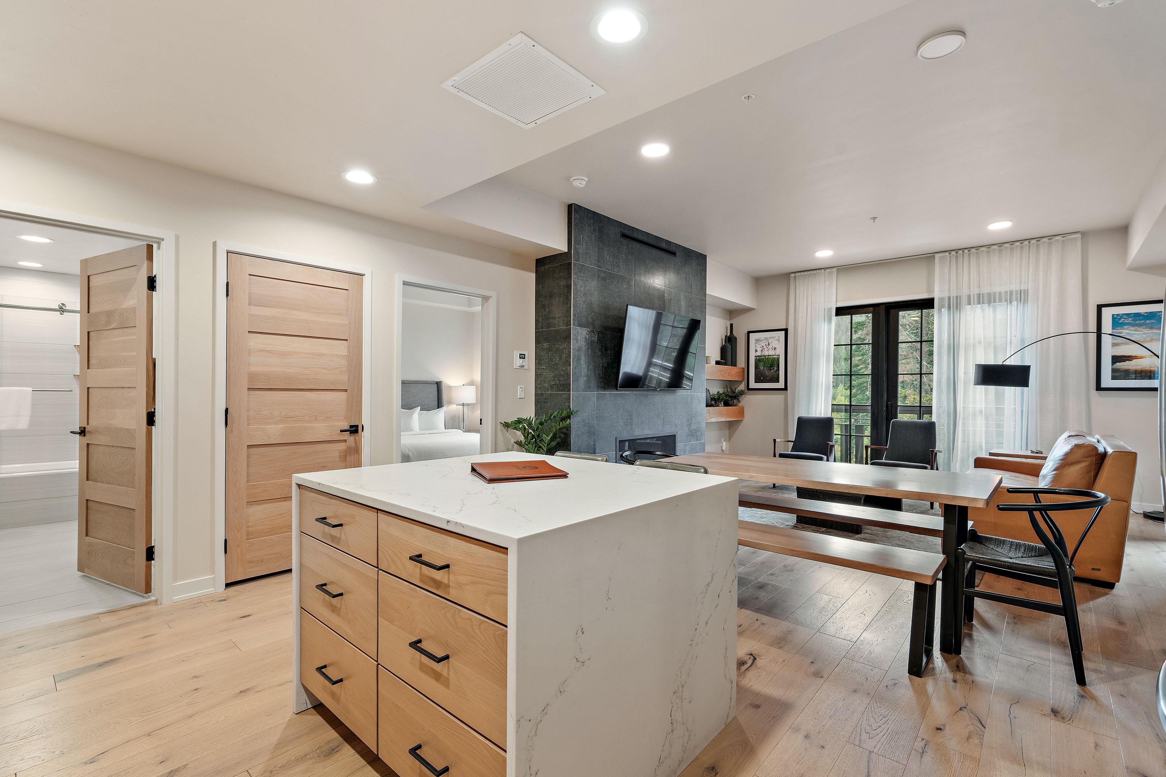 A modern kitchen with a central island, wooden cabinets, and a dining area with a table and chairs.