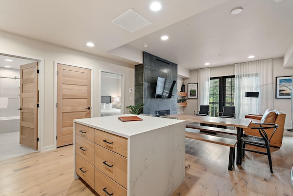 Una cocina moderna con una isla central, armarios de madera y un comedor con mesa y sillas.