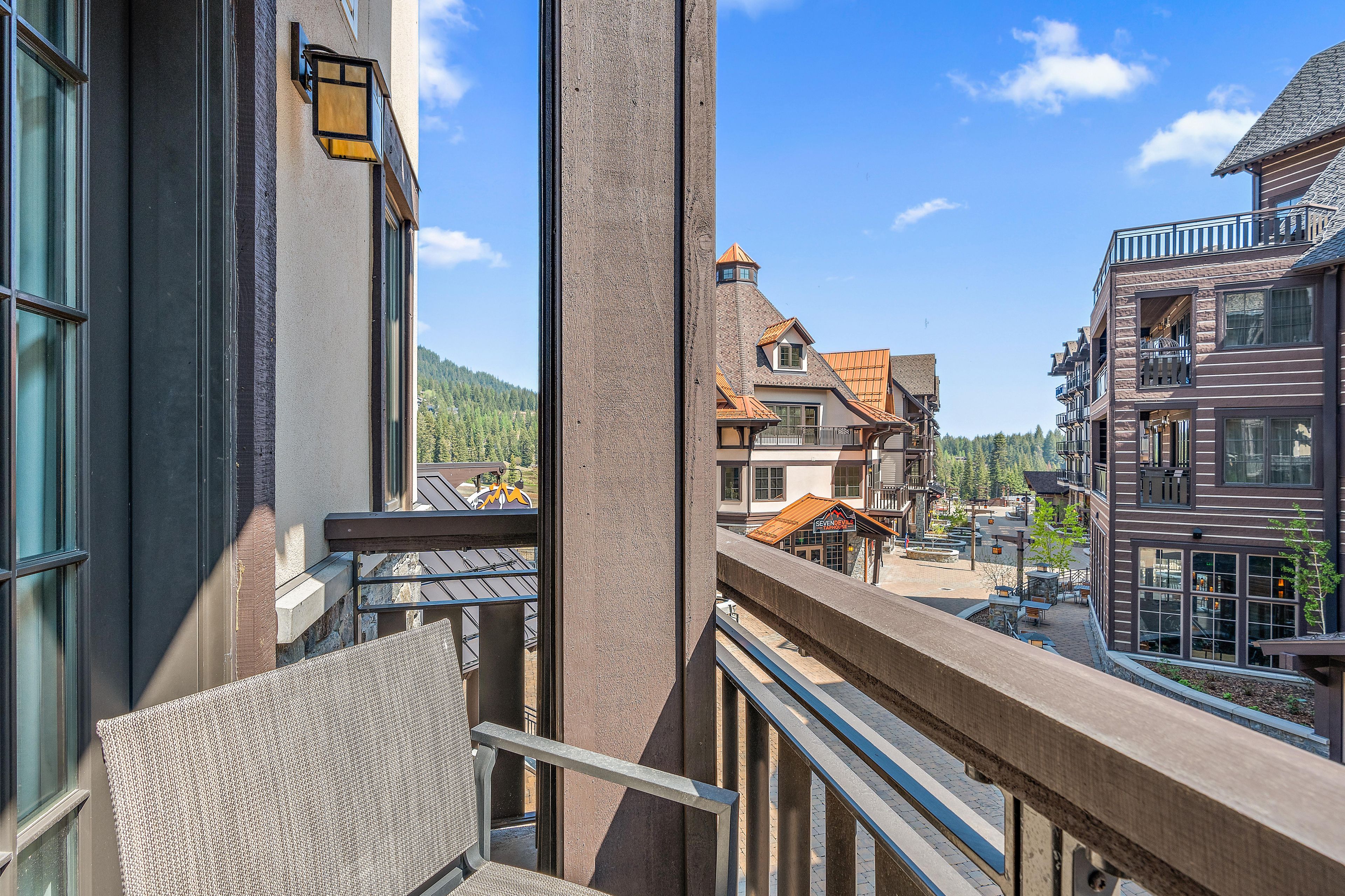 Un balcon donnant sur une place de ville, des bâtiments et une montagne au loin.