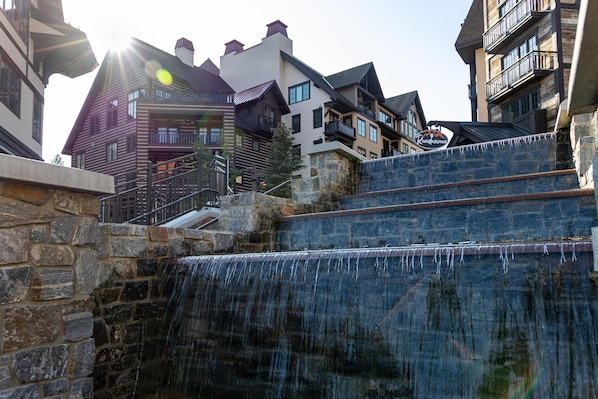 A stone staircase leading to a wooden building with a waterfall feature. - Happy Aspen | Includes Two 1-Day Lift Tickets (Tamarack)
