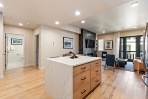 A modern kitchen with a central island, wooden flooring, and a dining area with a sofa and chairs. - Happy Aspen | Includes Two 1-Day Lift Tickets (Tamarack)