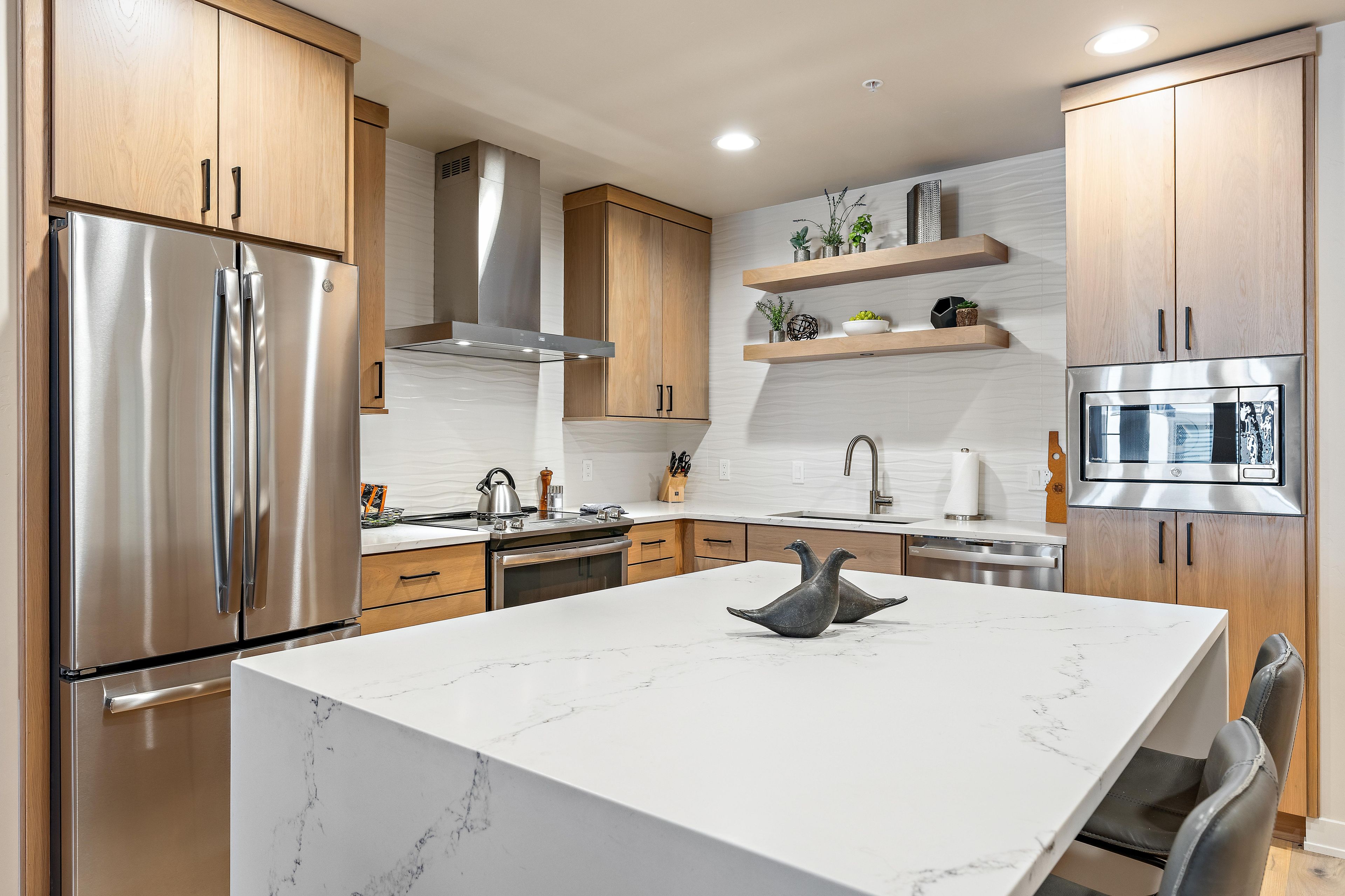 Een moderne keuken met roestvrijstalen apparatuur, houten kastjes en marmeren aanrechtbladen.