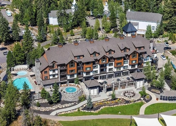 Un lodge de varios pisos con piscina, asientos al aire libre y un jardín ajardinado.