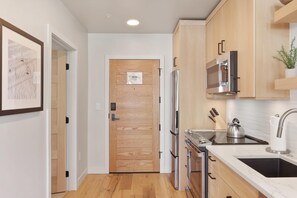 A modern kitchen with wooden cabinets, stainless steel appliances, and a marble countertop. - Falcon's Nest | Includes Two 1-Day Lift Tickets (Tamarack)