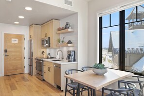 A modern kitchen with wooden cabinets, stainless steel appliances, and a large window offering a view of a snowy landscape. - Falcon's Nest | Includes Two 1-Day Lift Tickets (Tamarack)