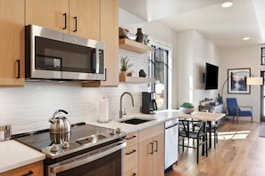 Una cocina moderna con electrodomésticos de acero inoxidable, armarios de madera y un comedor con mesa y sillas.
