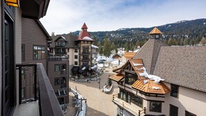 Une station de ski avec des bâtiments traditionnels en bois, une place centrale et, en arrière-plan, des montagnes enneigées.